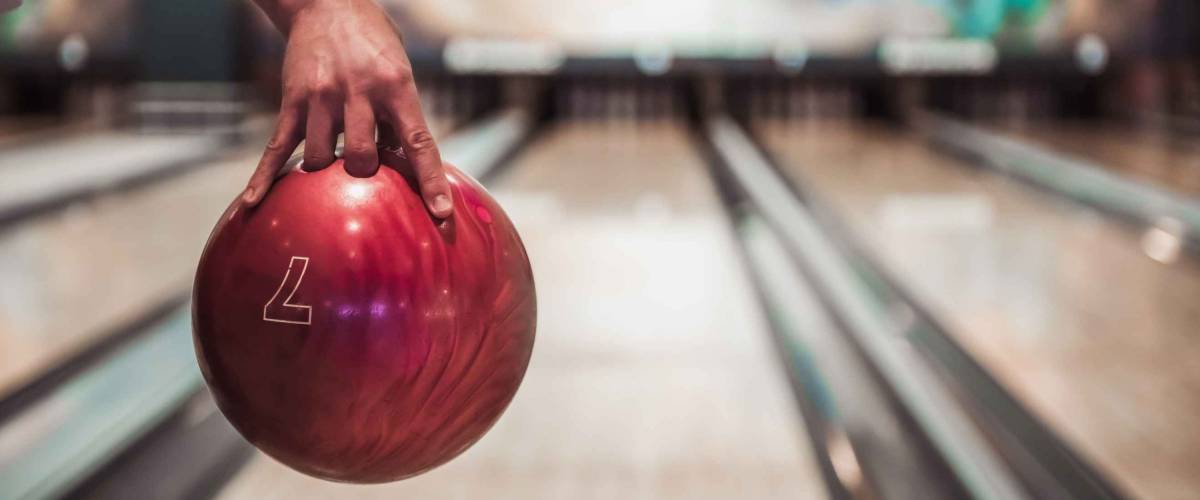 Man's hand holding a red bowling ball ready to throw it