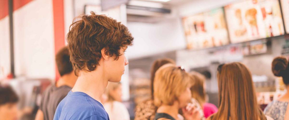 young teenager standing in a queue to receive the fastfood package
