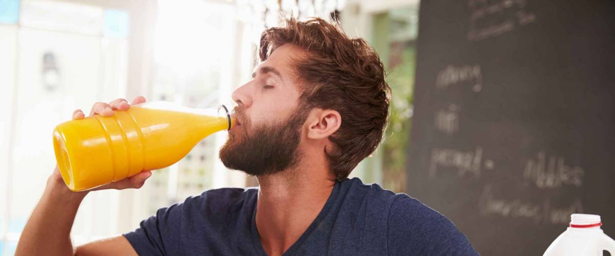Young Man Eating Breakfast And Drinking Orange Juice