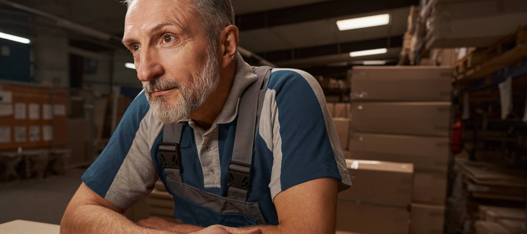A man, working in a warehouse, deep in thought.