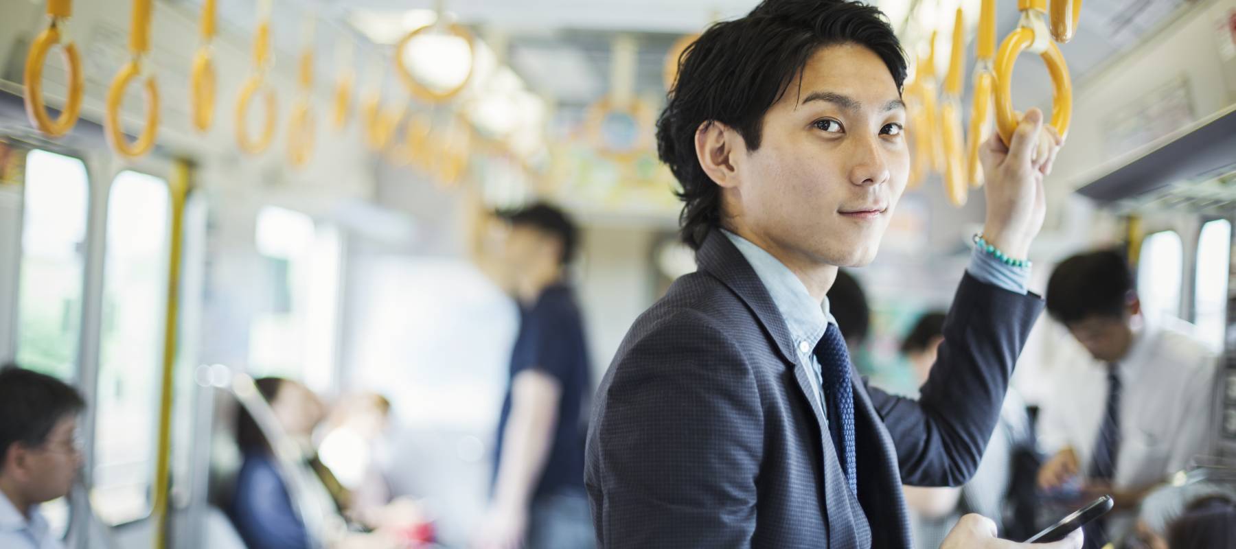 Young professional man looks up from his hone as he takes the bus to work.