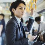 Young professional man looks up from his hone as he takes the bus to work.