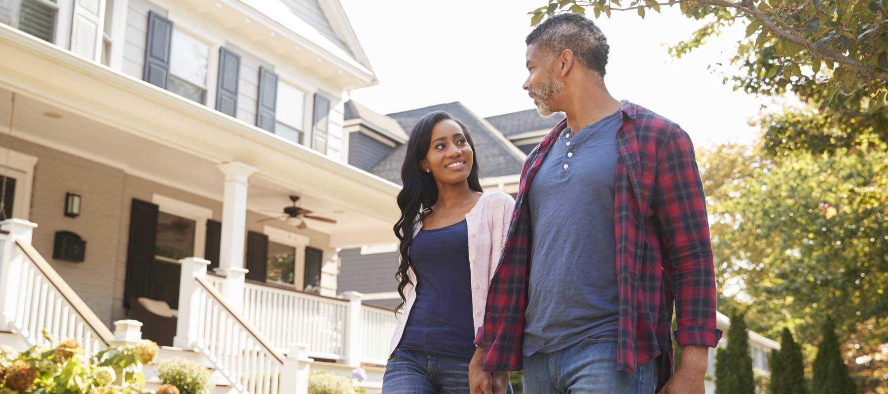A couple holds hands and walks down a residential street.