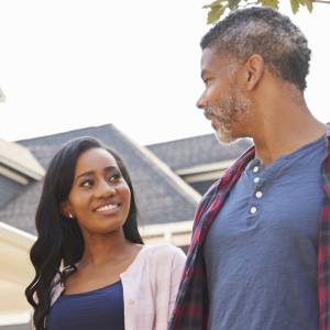A couple holds hands and walks down a residential street.