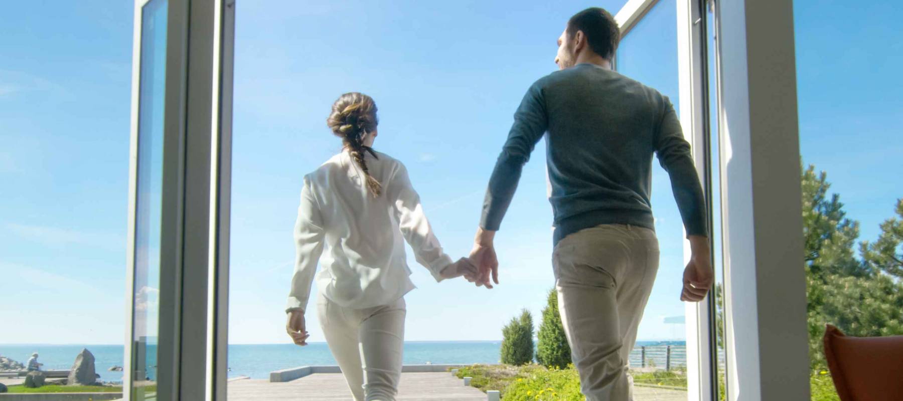 Happy Young Couple Holding Hands  Runs out of Their Home onto the Terrace with the Seaside View.