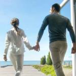 Happy Young Couple Holding Hands  Runs out of Their Home onto the Terrace with the Seaside View.