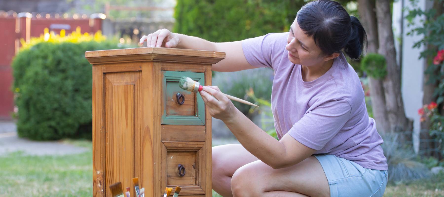 A woman prepares a piece of old furniture for resale.