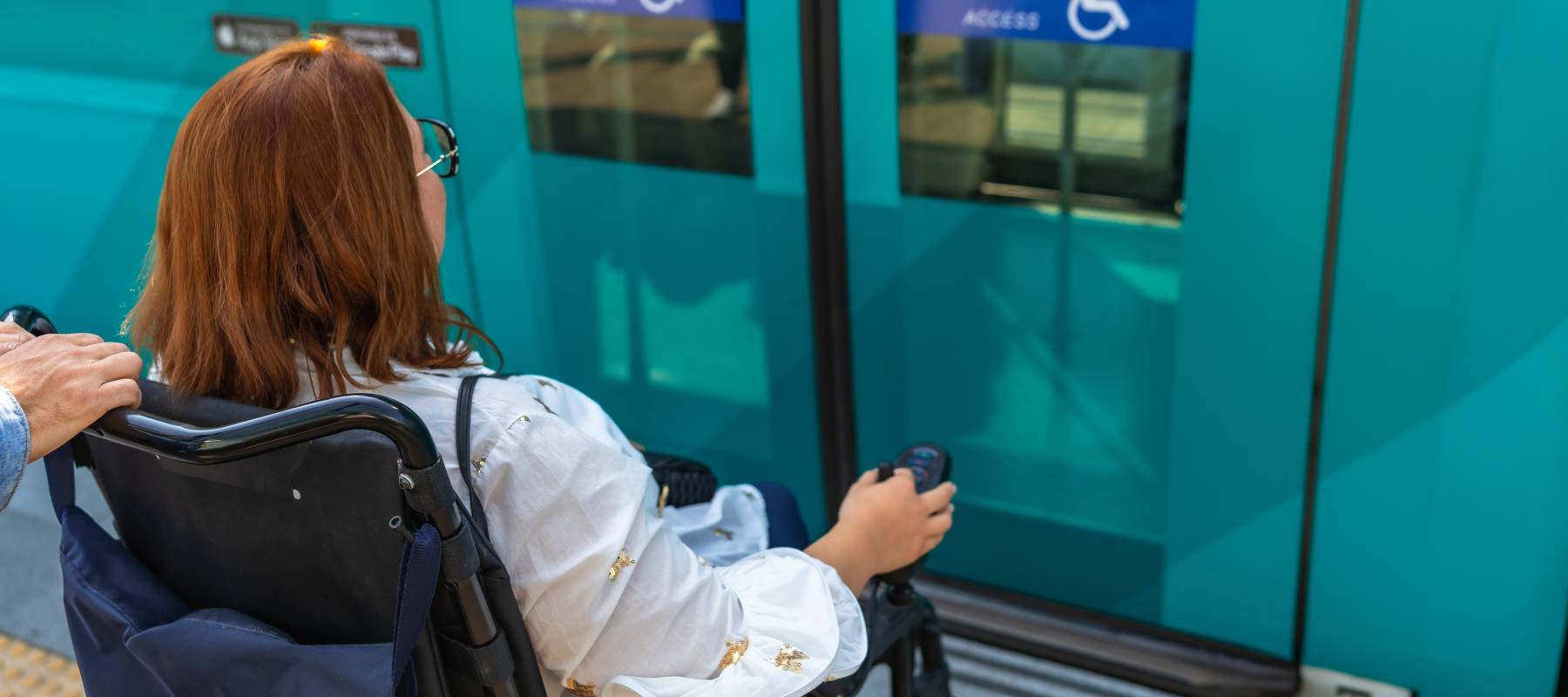A woman using a wheelchair enters a train car.
