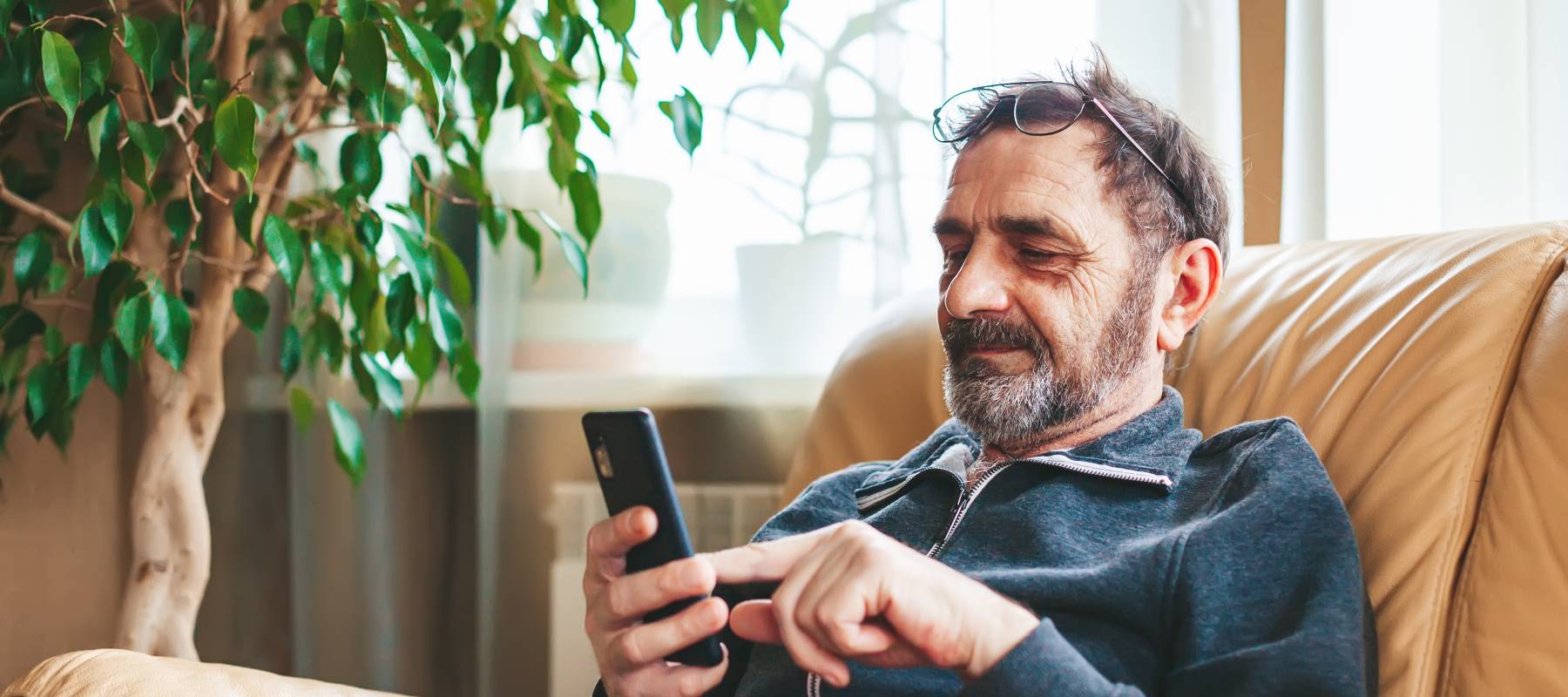An older man looks at spam texts at home