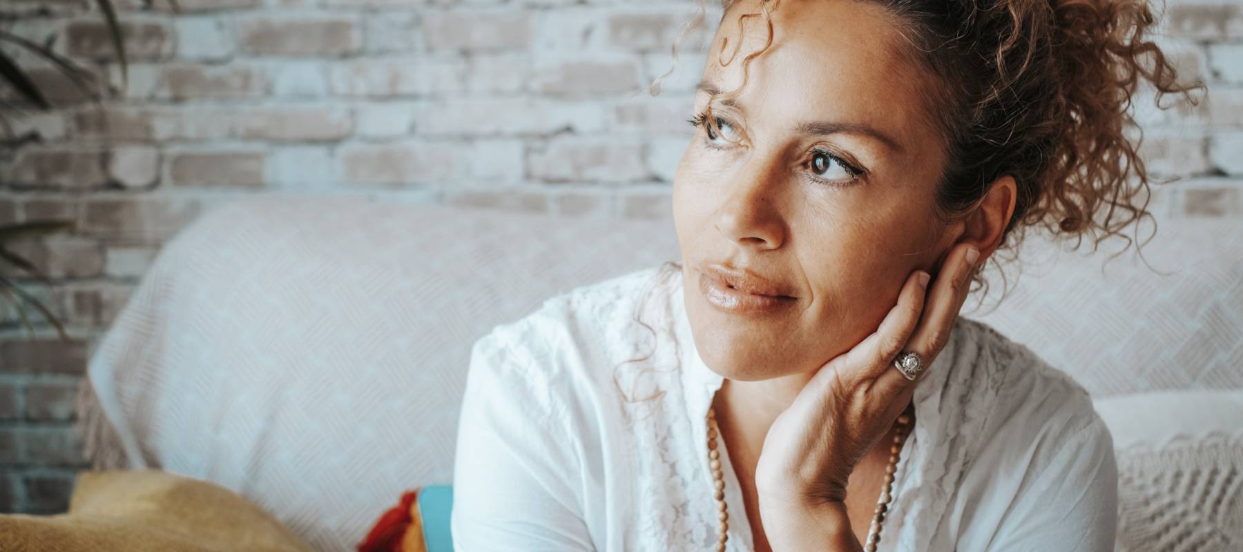 Pensive middle-aged woman at home sitting on the sofa.