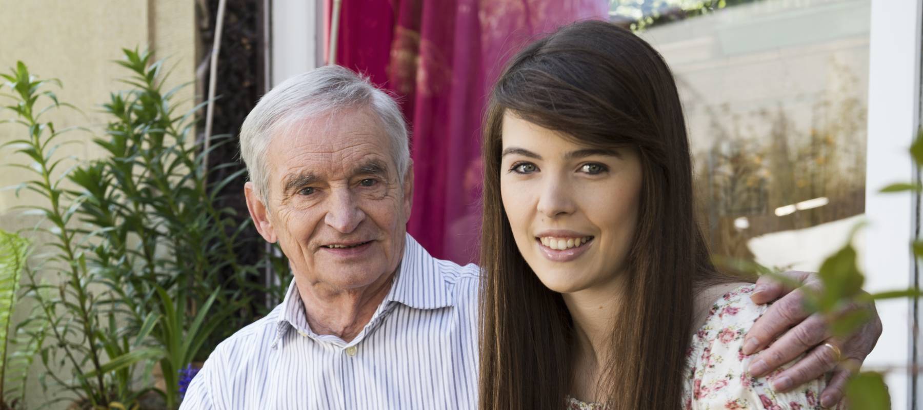Older gentleman with white hair and his daughter enjoying a sunny day on the porch.