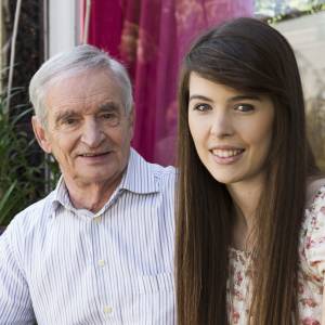 Older gentleman with white hair and his daughter enjoying a sunny day on the porch.