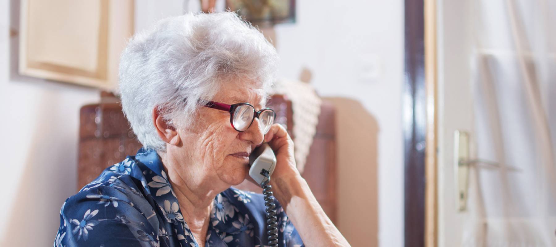 Older woman talking on the phone. Con artists are targeting older Americans in lottery scams.