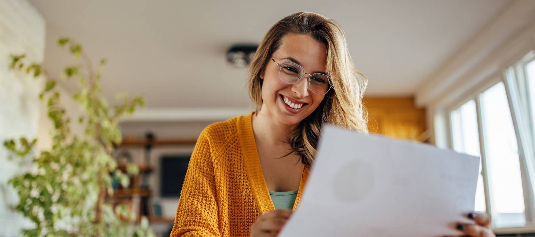 A young woman smiles while reading a document.