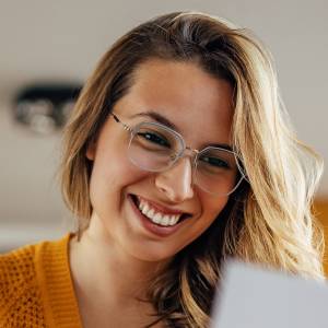 A young woman smiles while reading a document.