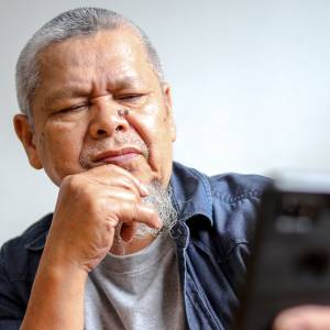 An older man looks at his smartphone confusingly.