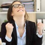 Excited businesswoman celebrating success looking above at office