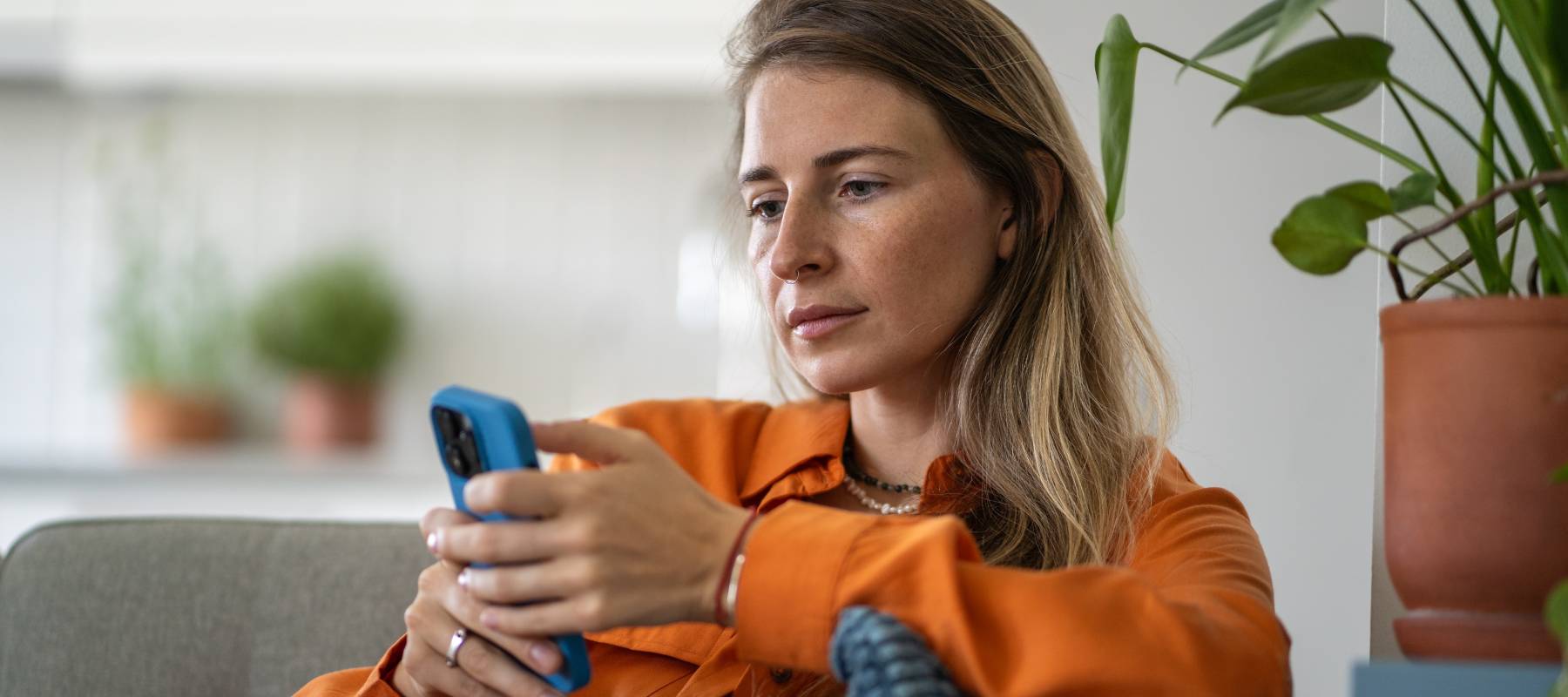 Middle-aged woman deeply focused on phone browsing.