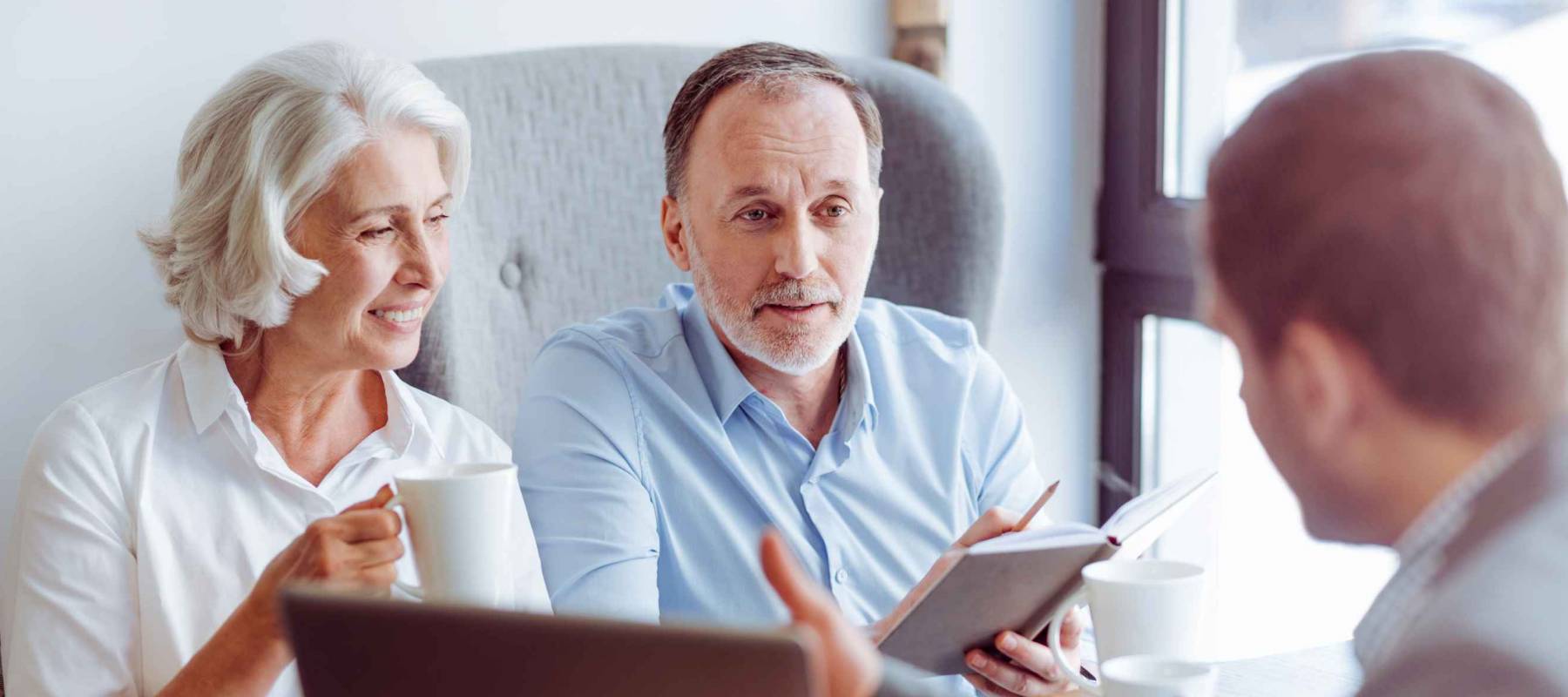 Older couple sitting with man at desk, talking animatedly