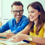 Happy couple at home paying bills with laptop