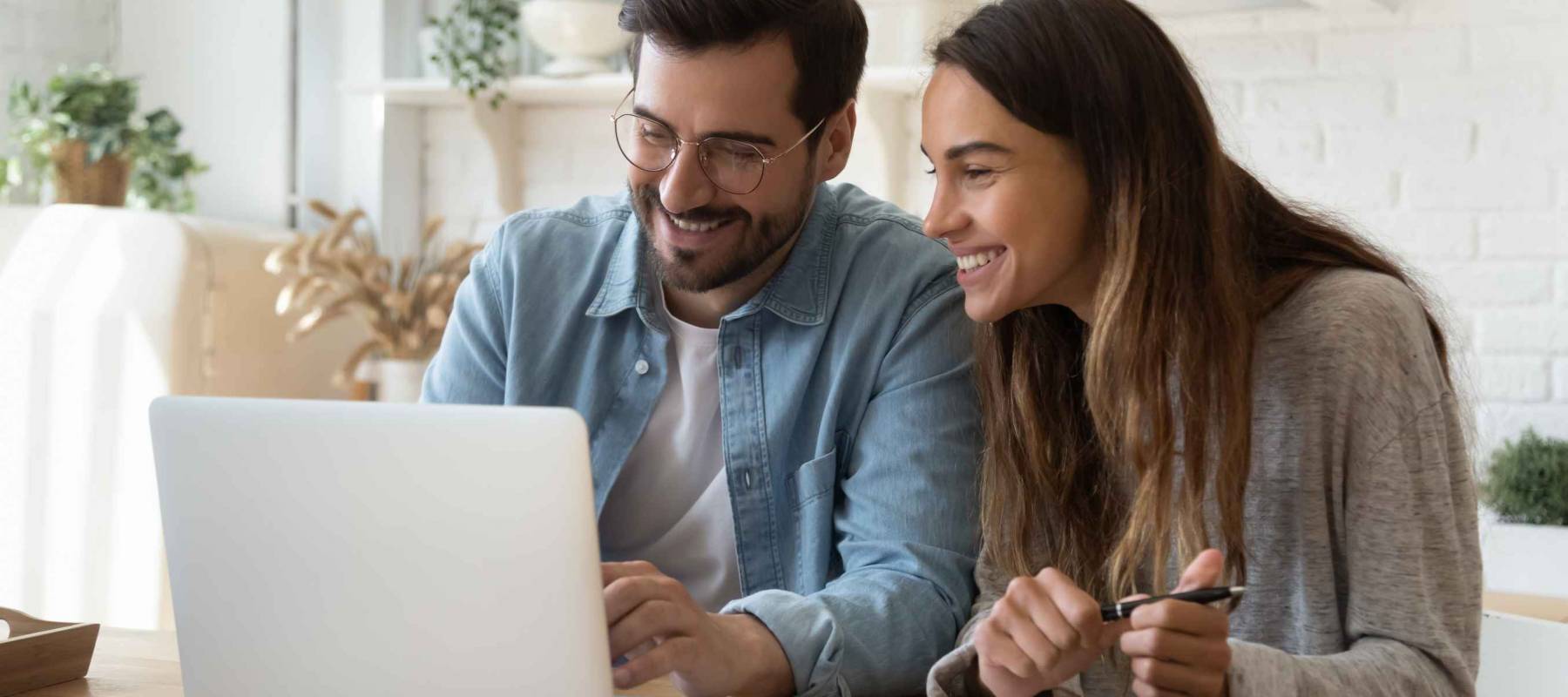 Happy young couple husband and wife using laptop computer.