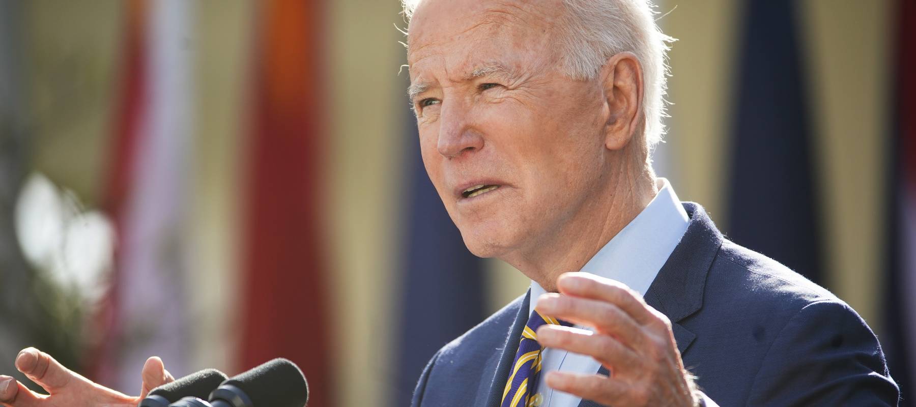 Joe Biden speaks at a podium with his hands up, concerned look on his face