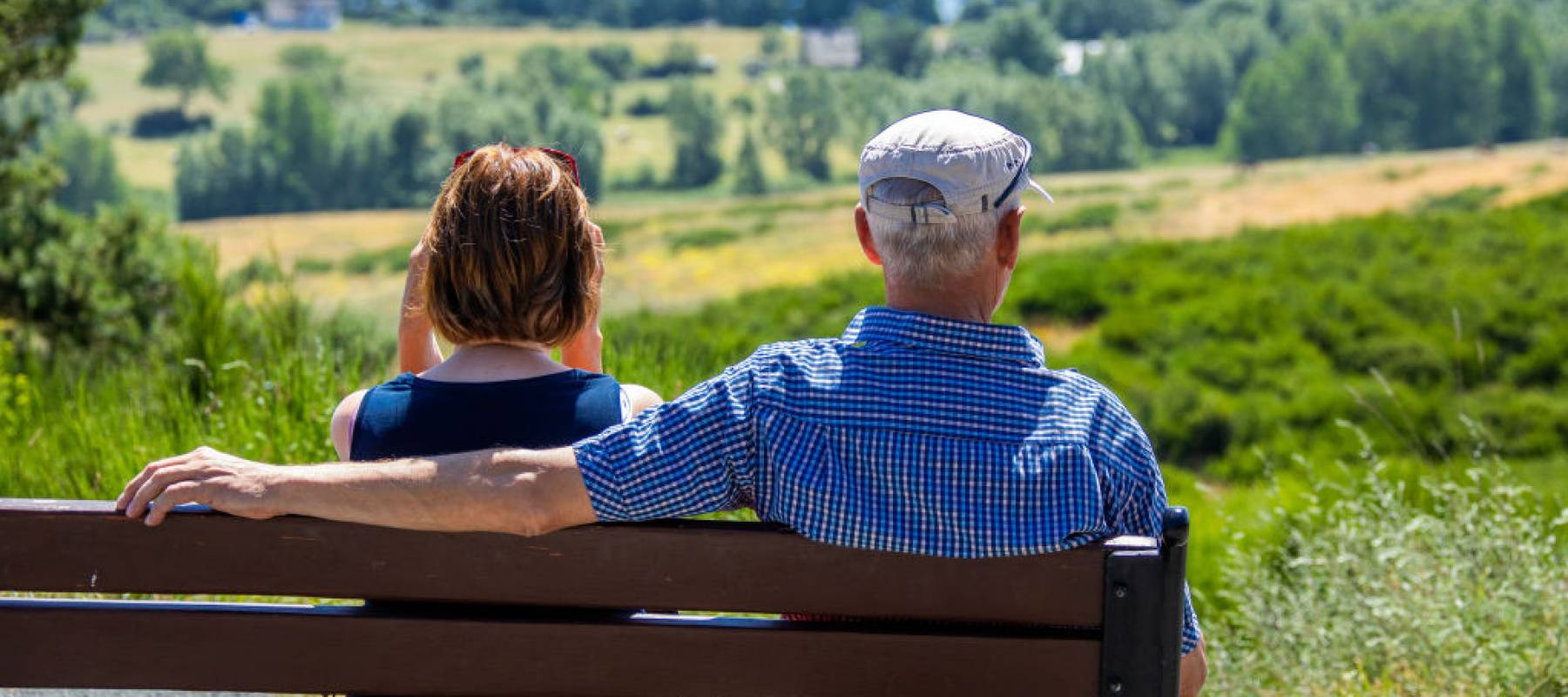 Retired couple sit on a bench in front of the panorama of the Baltic Sea island of Hiddensee.