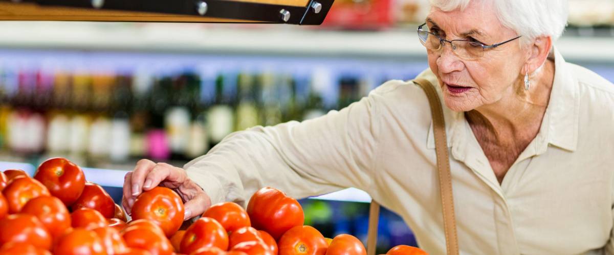 Senior woman choosing her tomatoes in supermarket