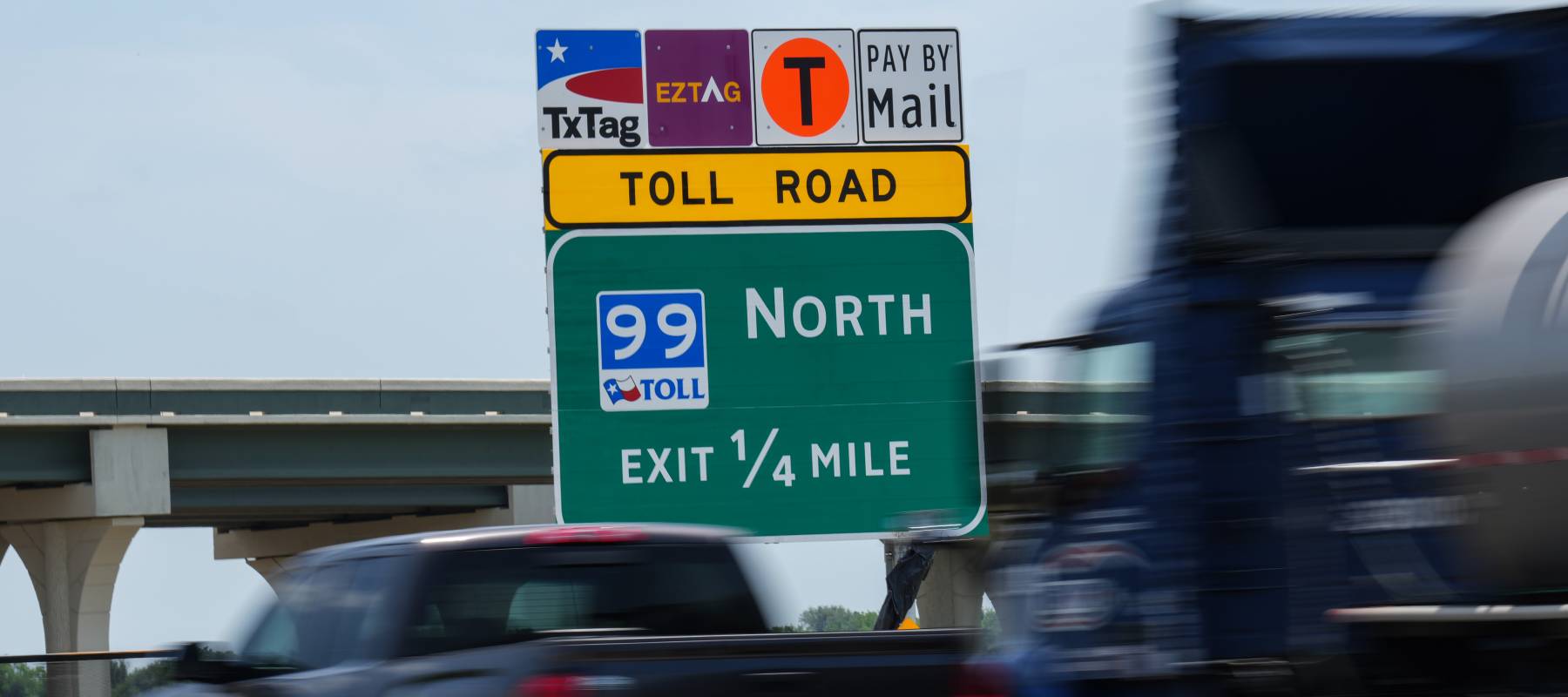 Trucks pass a sign directing drivers to SH 99 Grand Parkway Wednesday, May 18, 2022.