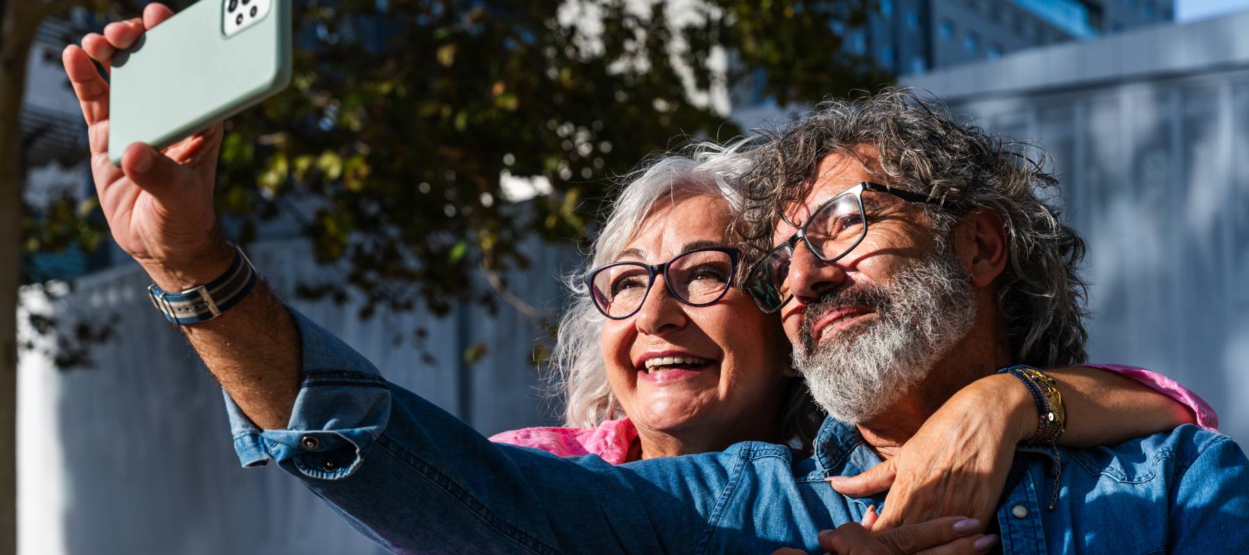 Smiling older couple snapping a selfie outdoors.