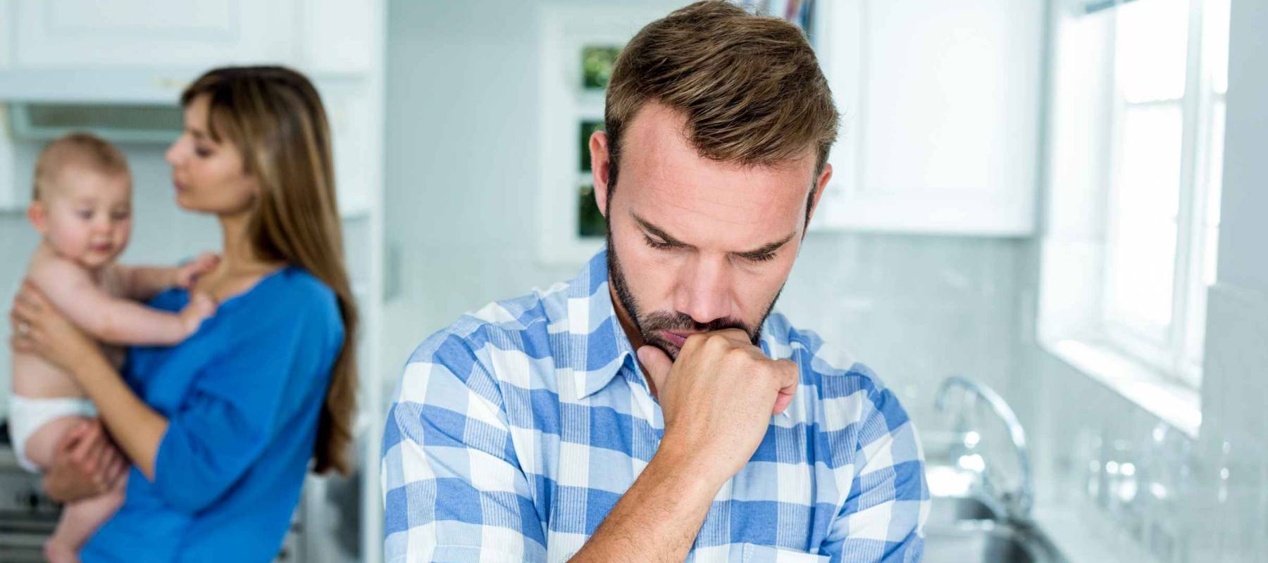 Upset man with family in background at kitchen