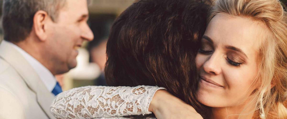 Bride closes her eyes hugging mother tender