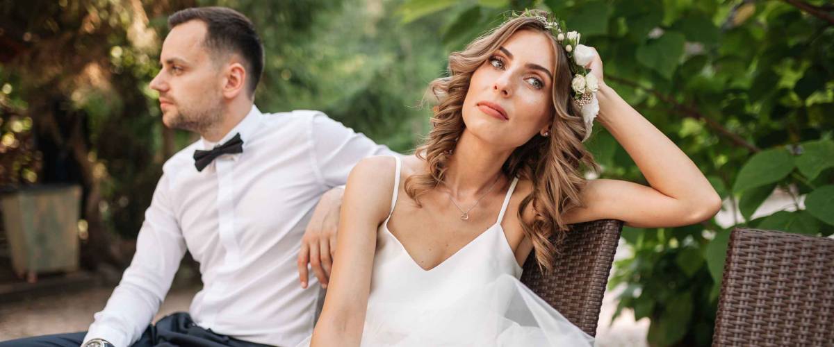 Newlywed coupe sitting on a sofa angry at each other in a middle of an argument. Young couple problem concept outdoor.