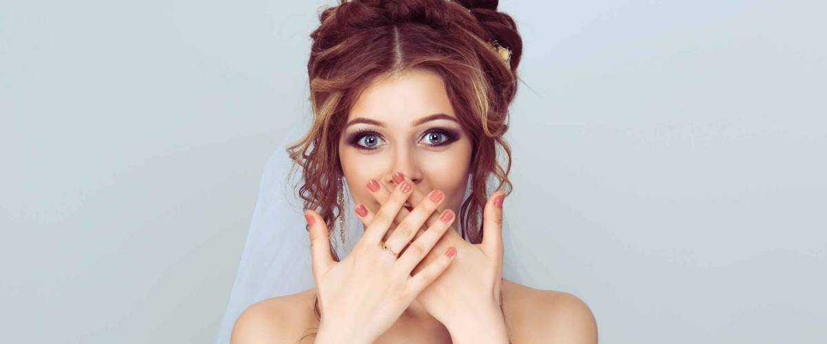 OMG. Pretty beautiful excited surprised woman bride girl covering her open mouth with hands, over light blue background. Positive face expression