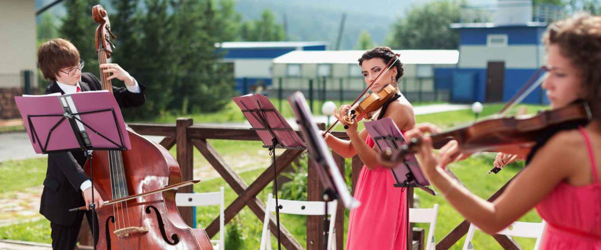 Quartet of classical musicians playing at a wedding outdoors near the river