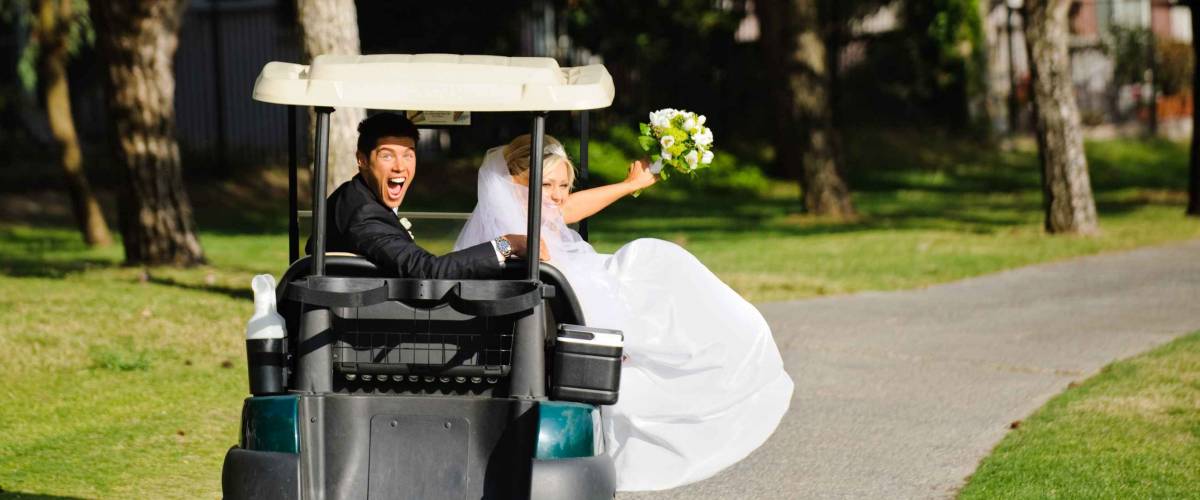 Bride and groom driving a golf cart