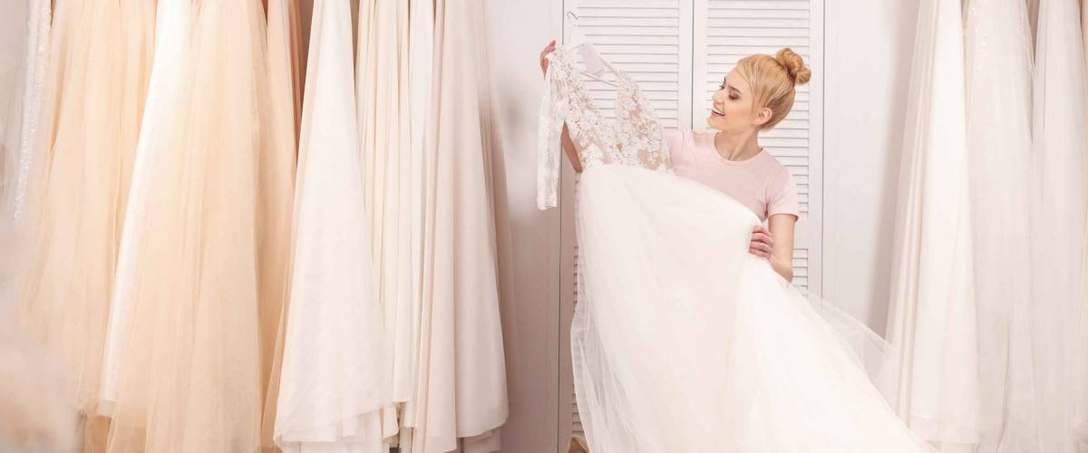 Attractive young woman is selecting bridal gown