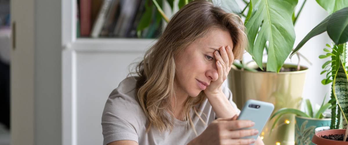 Confused woman doing facepalm gesture, touching head with palm looking at phone. Epic fail, reaction