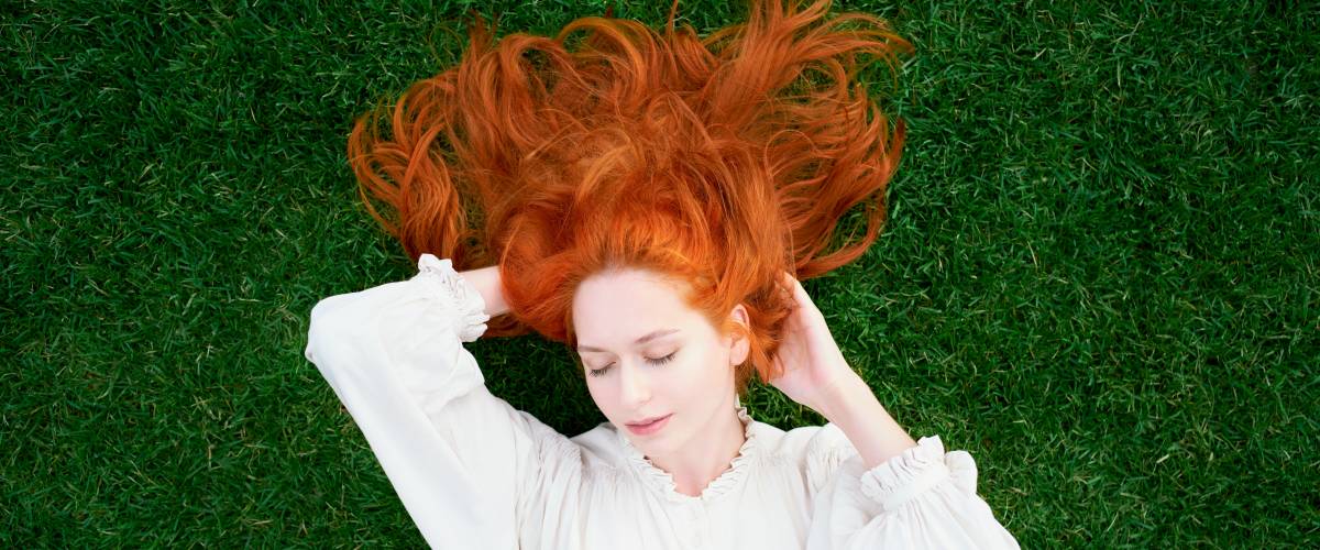 Redhead woman is resting on bright green lawn