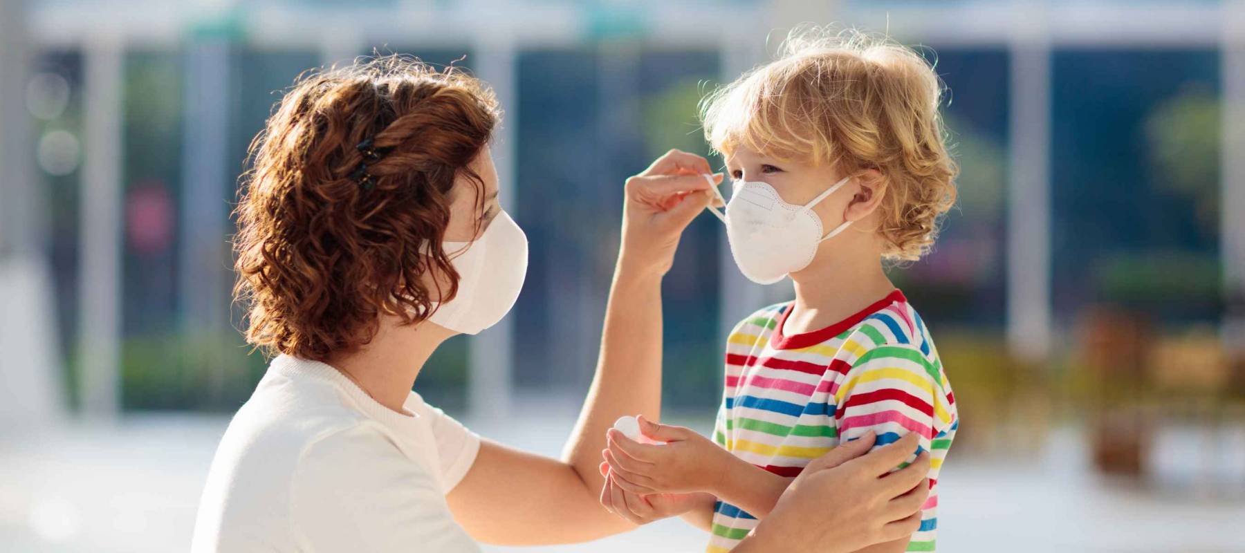 Mother putting on face mask on young child