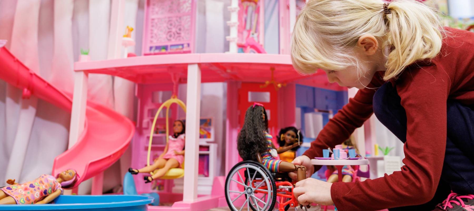 A girl playing with Barbies, as tariffs now impact how much extra the dolls can cost for shoppers ordering them into the U.S.