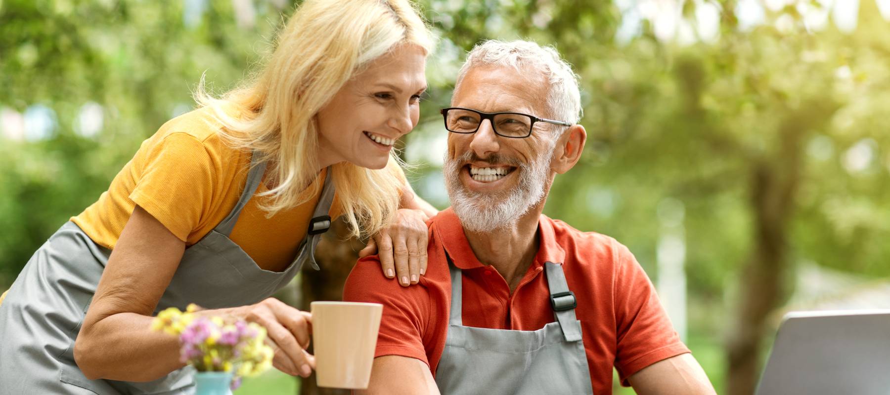A happy older couple using a laptop outdoors.