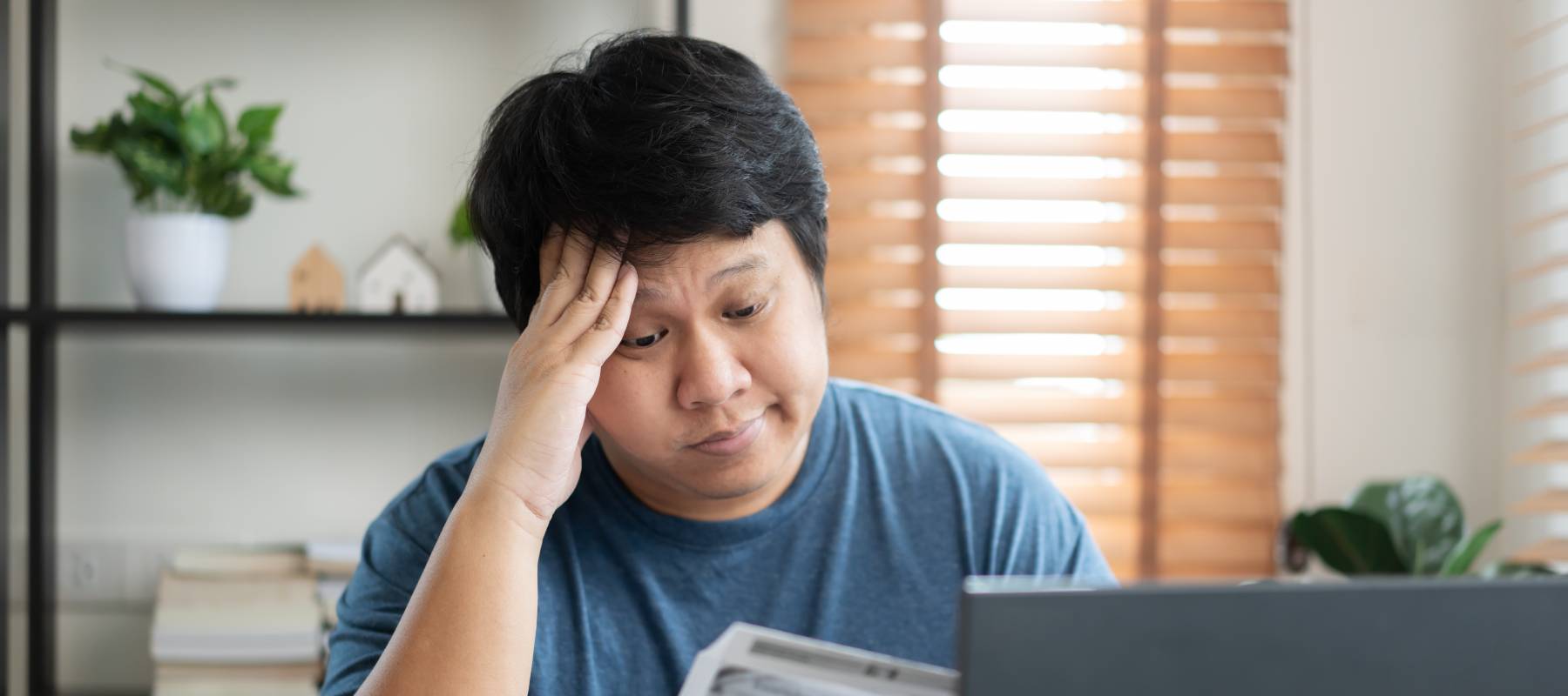 Worried middle-aged man reviewing documents in front of a computer.