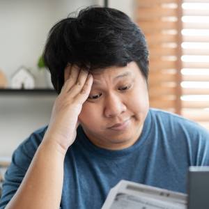 Worried middle-aged man reviewing documents in front of a computer.