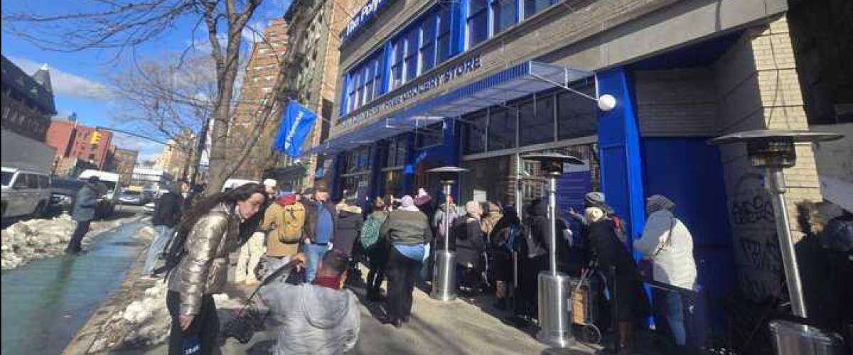 A crowd of people gather outside The Polymarket, a free grocery store popup in New York that opened on February 12, 2026.