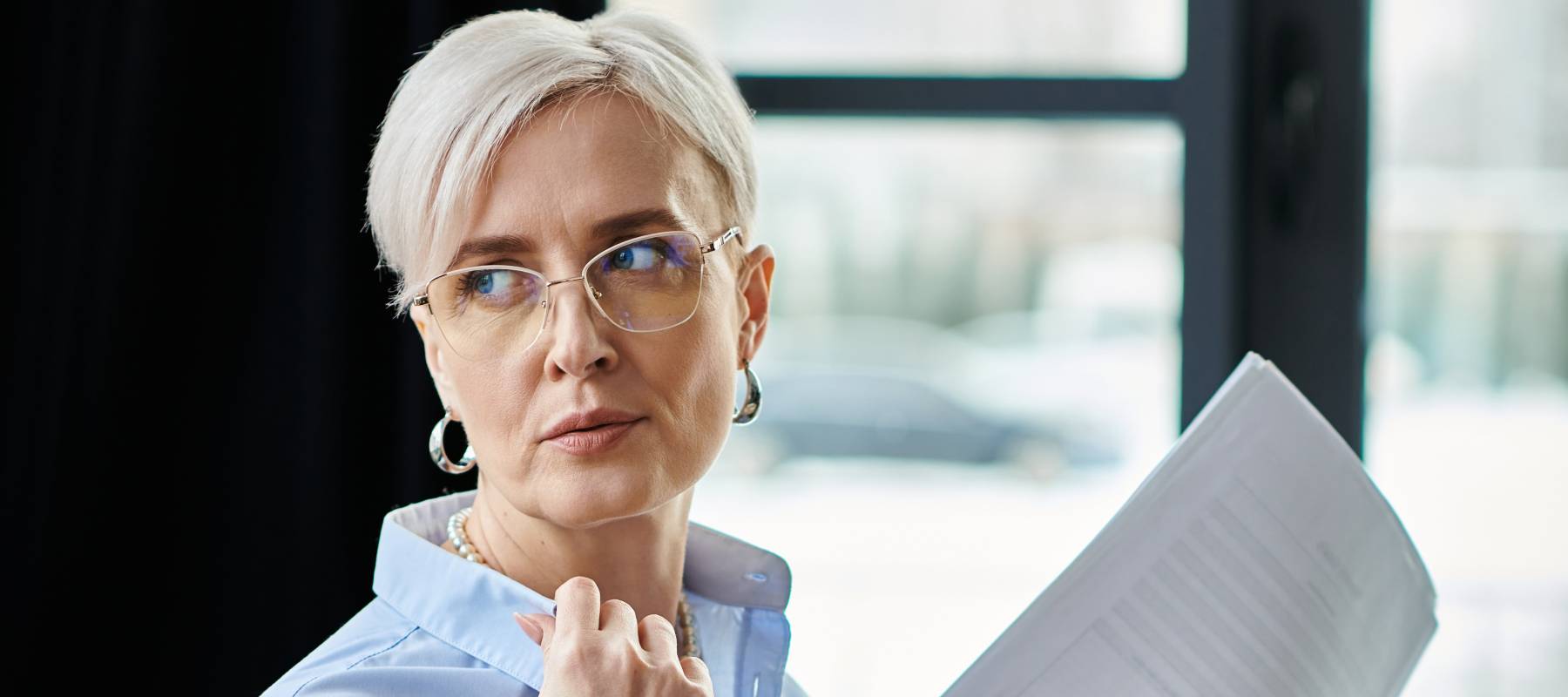 A business woman looks over her shoulder while wearing a blue blouse.