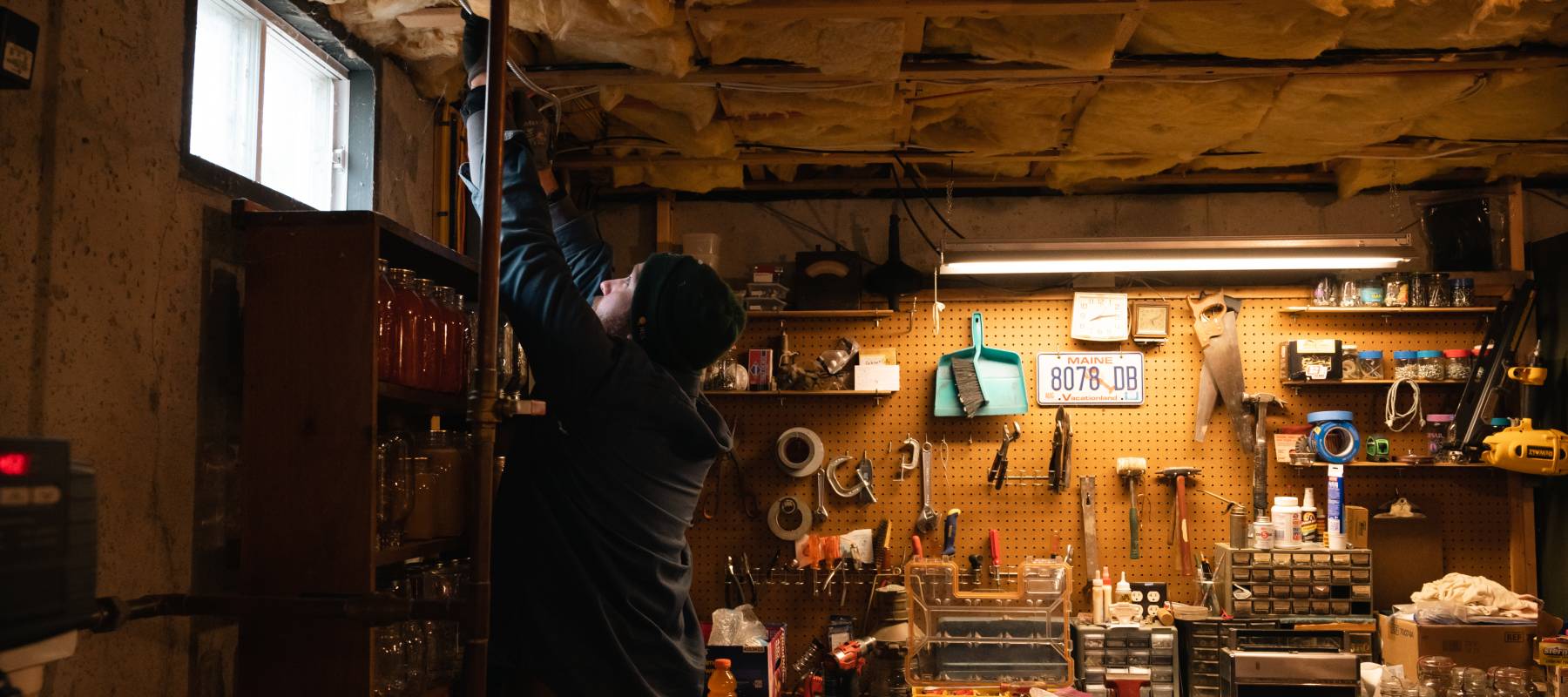 An electrician runs metal clad wire in a basement during a residential heat pump installation in Windham, Maine, Jan. 19, 2023.