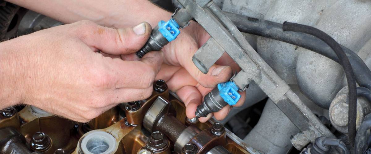 Car mechanic fixing fuel injector at  two camshaft gasoline engine