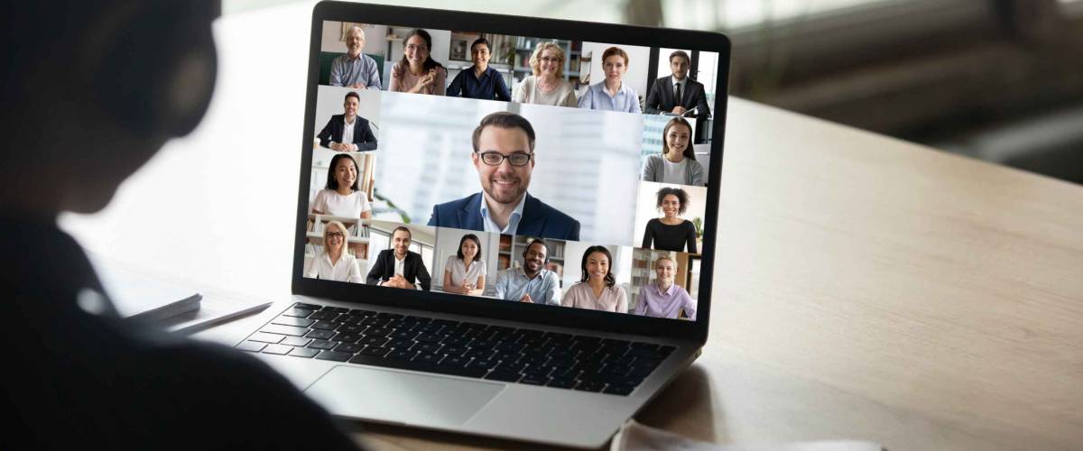 Back view of employee engaged in team Webcam conference on laptop.