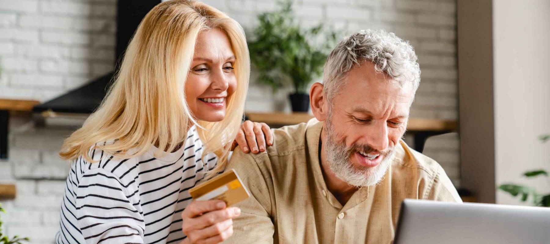 Happy couple using credit card for shopping online using laptop